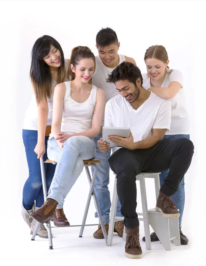 Gruppe junger Leute, sitzend auf Tablet schauend