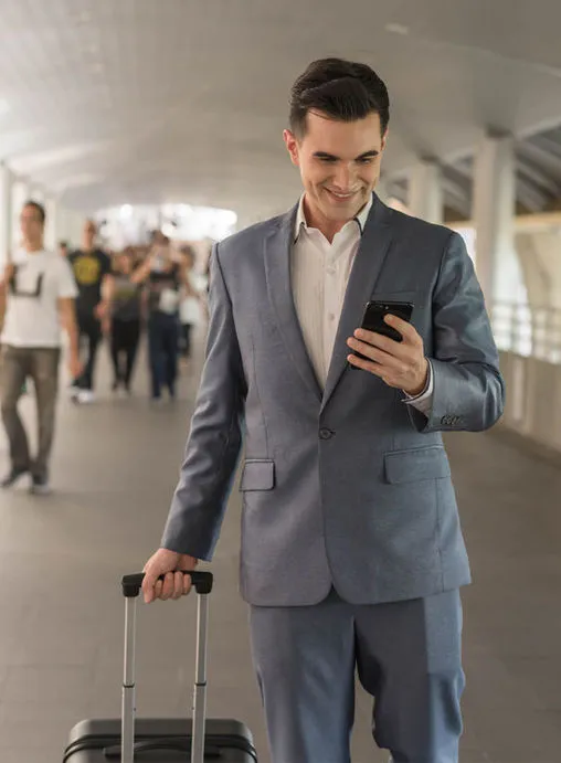 Mann, stehend, mit Rollkofer und Smartphone